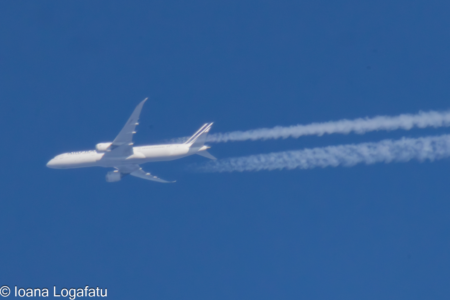 Jet soaring high above with contrails in clear sky